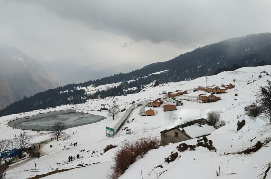 Snow-covered slopes and wooden huts at Auli in Uttarakhand