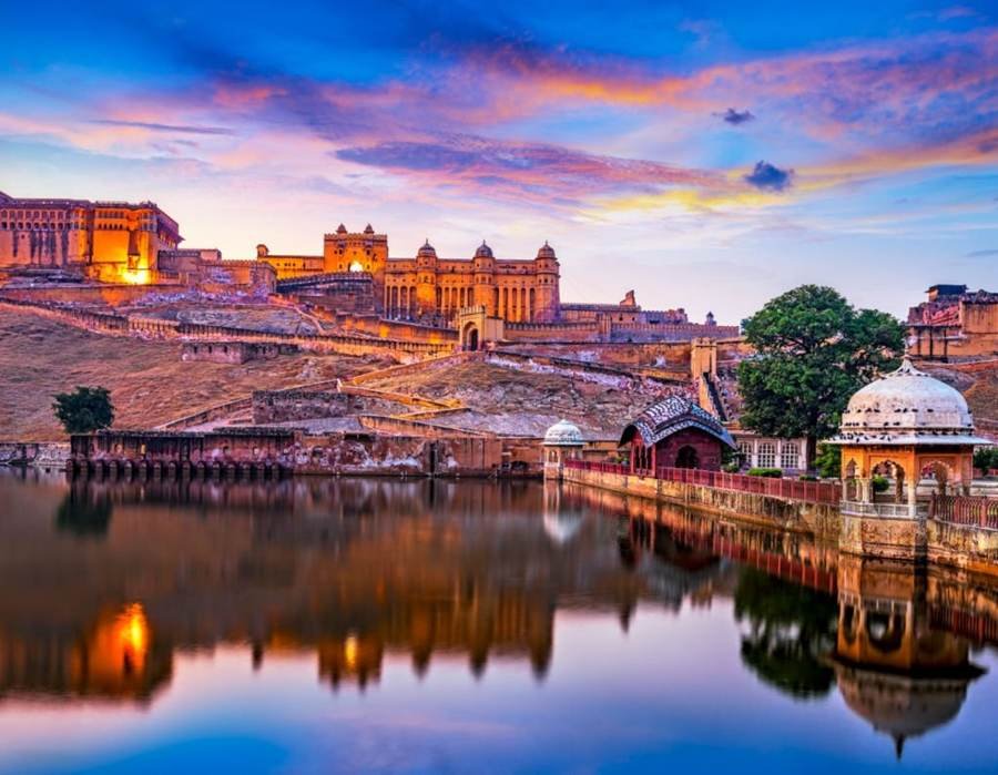 Amer Fort glowing at dusk above a lake near Jaipur