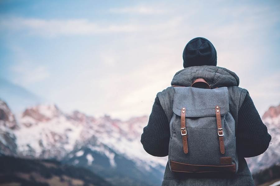 Backpacker looking at snow-covered mountains at dusk
