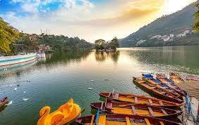 Boats on Naini Lake with hills and houses around it in Nainital