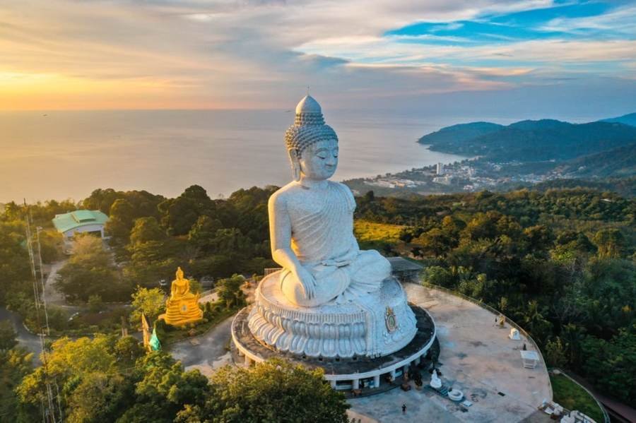 The Big Buddha statue on a hilltop above the coast in Phuket at sunset